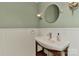 A stylish half bathroom featuring beadboard walls, a modern sink vanity, round mirror and modern lighting at 385 Gum Branch Rd, Charlotte, NC 28214