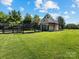 Charming barn with a fenced enclosure set on a green lawn under a blue sky with fluffy clouds at 4315 Hartis Grove Church Rd, Indian Trail, NC 28079