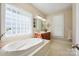 Relaxing bathroom with a soaking tub, dual sinks, and a window for natural light at 4570 Chanel Ct, Concord, NC 28025