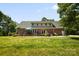 Back view of two-story brick home with lawn, trees, and patio at 4570 Chanel Ct, Concord, NC 28025