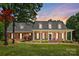 Charming brick home with a covered front porch, white columns, and meticulously landscaped front yard at sunset at 4570 Chanel Ct, Concord, NC 28025
