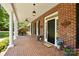 Charming covered front porch with brick flooring, white columns, and a welcoming entrance adorned with flowers and décor at 4570 Chanel Ct, Concord, NC 28025