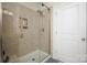 Modern tiled shower featuring a glass door, shower head, and built-in storage shelves at 5063 Gribble Ln, Lancaster, SC 29720