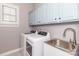 Laundry room featuring modern washer and dryer, utility sink, and light blue cabinets at 5321 Kathryn Blair Ln, Charlotte, NC 28226