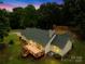 Enjoy this well-maintained home with a spacious wooden deck overlooking a lush backyard and tree coverage at twilight at 5903 Wm Griffin Rd, Monroe, NC 28112