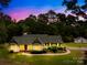 Inviting single-story home featuring beautiful landscaping, bay windows, and verdant tree coverage at twilight at 5903 Wm Griffin Rd, Monroe, NC 28112