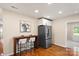 Open-concept kitchen with bar seating, stainless steel refrigerator, and hardwood floors at 6034 Tuckaseegee Rd, Charlotte, NC 28208
