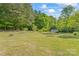 Large grassy backyard with an outdoor firepit and storage shed surrounded by mature trees at 743 Dream Ln, Salisbury, NC 28146