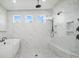 Bright bathroom featuring marble tile, pebble floor, frameless glass shower, and soaking tub at 1005 Grand Oak Dr, Waxhaw, NC 28173