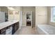 Bright bathroom with a tub, tiled floors, and white fixtures and cabinets at 1011 Potomac Rd, Indian Trail, NC 28079