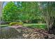 Spacious backyard featuring a brick patio with a built-in fire pit, green grass, and mature trees at 1012 Sudbury Ln, Matthews, NC 28104