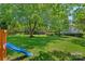 Spacious backyard featuring a playground set, mature trees, and lush green grass at 1012 Sudbury Ln, Matthews, NC 28104