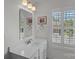 Bright bathroom featuring a white vanity with marble countertops and a large window with plantation shutters at 1012 Sudbury Ln, Matthews, NC 28104