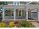 Inviting covered front porch with white railing, brick accents, and decorative hanging plants at 1012 Sudbury Ln, Matthews, NC 28104