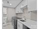 Bright laundry room featuring gray washer and dryer, white cabinetry, quartz counters, and stainless steel sink at 1012 Sudbury Ln, Matthews, NC 28104