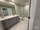 Modern bathroom with a double vanity, toilet, and marble-look tile shower at 12032 Lavinia Ln, Charlotte, NC 28277