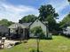 View of the home's backyard showcasing a small tree, air conditioning units, a basketball hoop, and patio area at 1212 Meadow Ln, Charlotte, NC 28205
