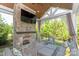 Inviting covered outdoor living space with stone fireplace, TV, comfortable seating, and views of the lush backyard at 1260 Thomas Knapp Pkwy, Fort Mill, SC 29715