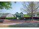 A community playground with green and blue equipment is bordered by lush green trees and bushes at 1260 Thomas Knapp Pkwy, Fort Mill, SC 29715