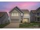 Charming two-story home with neutral siding, stone accents, and a manicured lawn with twilight sky at 128 Championship Dr, Mooresville, NC 28115