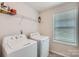 Bright laundry room featuring a side-by-side washer and dryer, a wire shelf, and a window at 128 Championship Dr, Mooresville, NC 28115