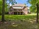 Expansive backyard view showcases a two-story brick home with a large deck and ample green space surrounded by mature trees at 130 Churchill Dr, Salisbury, NC 28144
