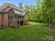 A spacious backyard is displayed with a two-story brick home featuring a deck and lush lawn bordered by tall, mature trees at 130 Churchill Dr, Salisbury, NC 28144