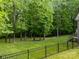 A backyard with a black metal fence and a lush, green yard bordered by trees at 130 Churchill Dr, Salisbury, NC 28144