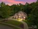 Beautiful brick home at dusk with lush landscaping, circular drive, and well-lit entrance for a welcoming appeal at 130 Churchill Dr, Salisbury, NC 28144