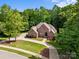 Aerial view of an impressive brick home featuring beautiful landscaping, a circular driveway, and mature trees providing privacy at 130 Churchill Dr, Salisbury, NC 28144