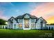 Stunning white brick home featuring a manicured green lawn and architectural details and a beautiful dusk sky at 1351 Highway 324 None, Rock Hill, SC 29730