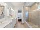 Bathroom showcasing double vanity, stylish lighting, quartz countertops, large glass enclosed shower, and view to bedroom at 13714 Jacks Ln, Pineville, NC 28134