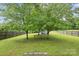 Open backyard with mature trees, wooden fence, and lawn at 1525 Moss Creek Dr, Harrisburg, NC 28075
