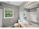 Well lit bathroom featuring window, tile flooring, wood cabinets, sink and bath with shower at 1525 Moss Creek Dr, Harrisburg, NC 28075