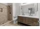 A well-lit bathroom with a tiled shower, a double vanity, and a large mirror at 16610 Amberside E Rd, Cornelius, NC 28031