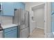 Stainless steel refrigerator and appliances complement blue cabinetry in this modern kitchen next to laundry area at 16610 Amberside E Rd, Cornelius, NC 28031