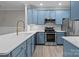 Modern kitchen featuring quartz counters, stainless steel appliances and vibrant blue cabinets offering a gourmet experience at 16610 Amberside E Rd, Cornelius, NC 28031