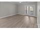Bright living room with wood-look floors, a ceiling fan, and a glass door leading to an outdoor area at 16610 Amberside E Rd, Cornelius, NC 28031
