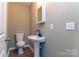 Neutral half bathroom showcasing a pedestal sink with black fixtures, modern mirror, toilet, and laminate flooring at 209 W Marsh St, Salisbury, NC 28144