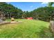 Expansive backyard with lush lawn, brick fire pit, playhouse, and red shed surrounded by mature trees at 2315 Perry Rd, Denver, NC 28037