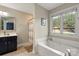 Bathroom featuring a soaking tub, window, and dark-stained vanity at 2315 Perry Rd, Denver, NC 28037