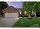 Charming brick home with a well-manicured lawn, two-car garage, and inviting front entrance at dusk at 2315 Perry Rd, Denver, NC 28037