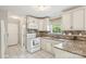 Well-lit kitchen featuring white cabinets, granite countertops, and updated appliances at 3223 Rheinwood Ct, Matthews, NC 28105