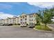 Charming condo building with multiple balconies and manicured landscaping in a well-lit parking area at 4072 Town Center Rd, Harrisburg, NC 28075