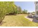 Expansive backyard lawn with mature trees, featuring a brick patio with outdoor dining area for entertaining at 4117 Wallbrook Dr, Matthews, NC 28105
