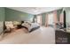 This spacious bedroom offers comfort with soft carpet, a ceiling fan, and serene green walls at 4117 Wallbrook Dr, Matthews, NC 28105
