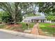 Inviting home featuring a red brick pathway, lush lawn, and mature trees at 5601 Carmel Station Ave, Charlotte, NC 28226