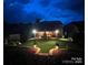 Beautifully landscaped backyard at night with ambient lighting, spacious lawn, and covered patio at 724 Lagan Ct, Fort Mill, SC 29715