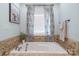 Close up of a tiled tub with tile surround and window with curtain at 945 Songbird St, Lancaster, SC 29720