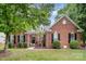 Inviting one-story red brick home with lush landscaping, black shutters, and a cozy front entrance at 10011 Spring Park Dr, Charlotte, NC 28269
